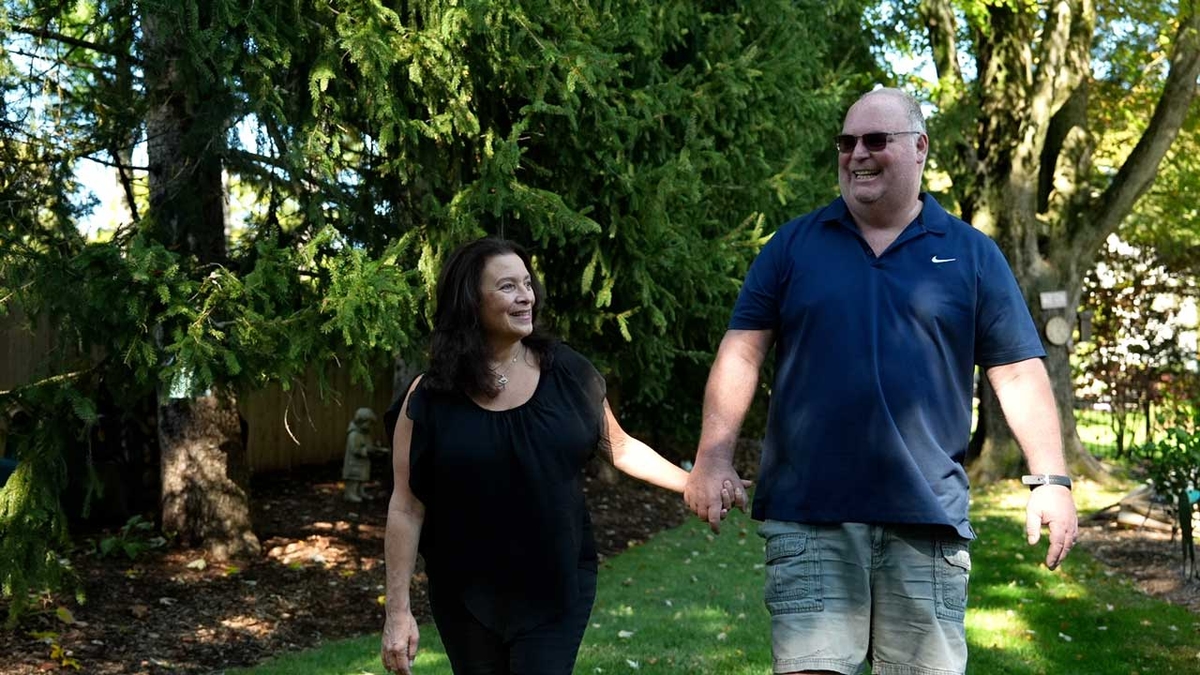 a woman and a man couple holding hands walking in a park. 