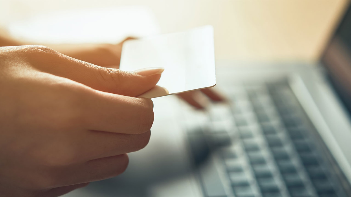 holding credit card in front of computer screen